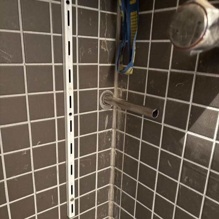 Stútar fyrir sturtu komnir í rétta hæð í flísalögðum vegg.
